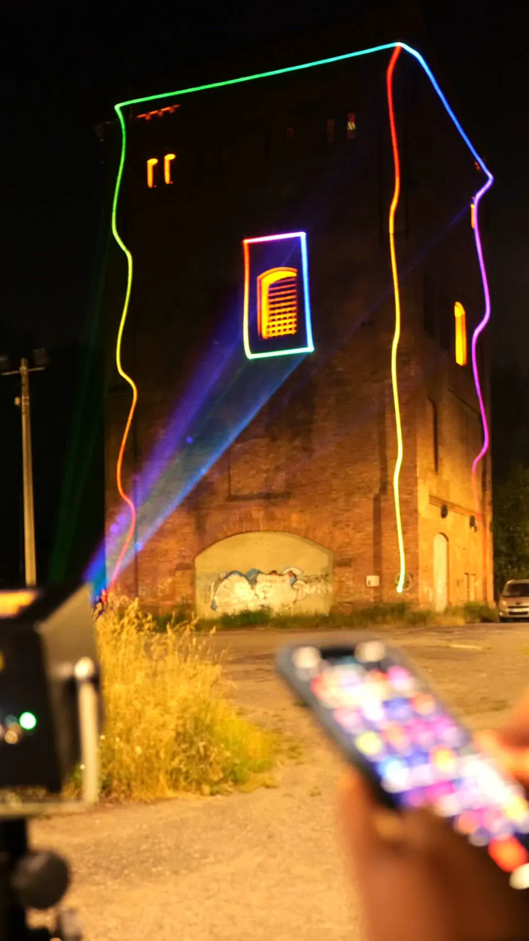 A LaserCube outlining a brick tower in coloured lines, controlled from a phone