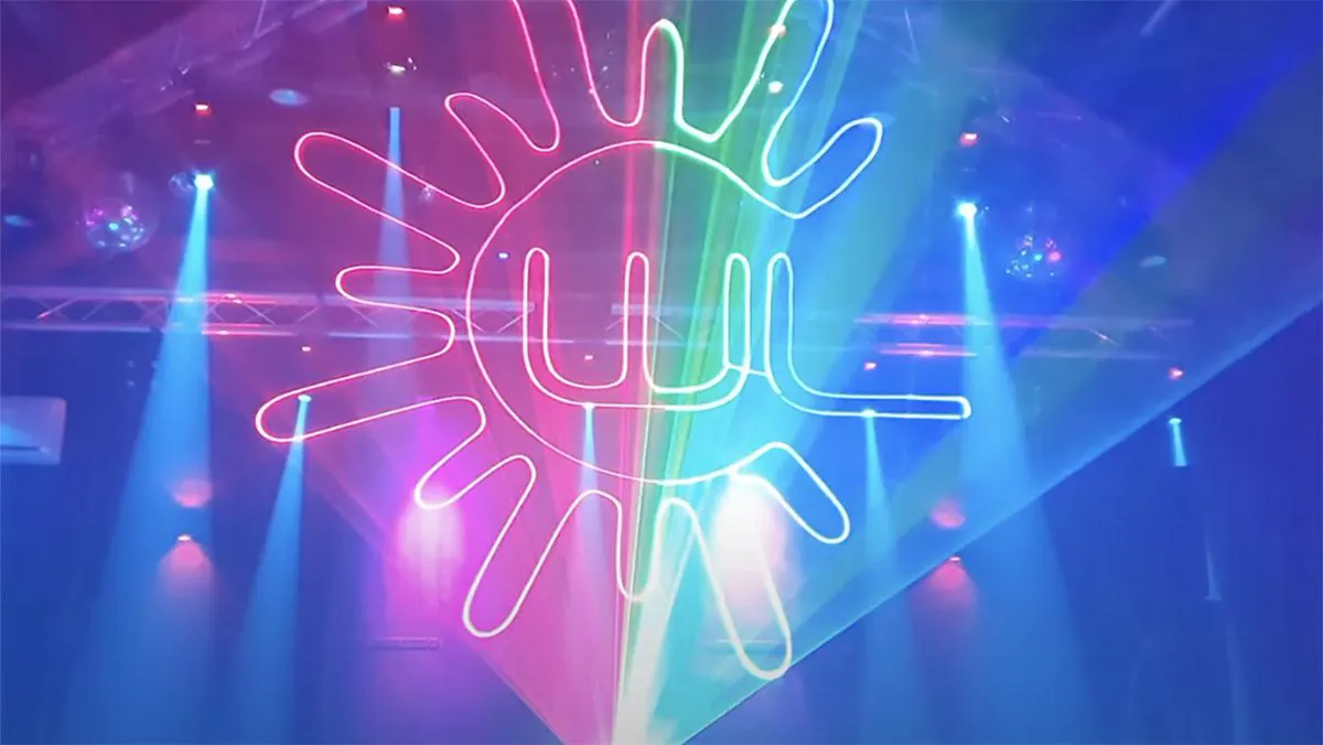 Laser projection through smoke on a stage showing green and red laser lights, with the Wicked Laser logo.