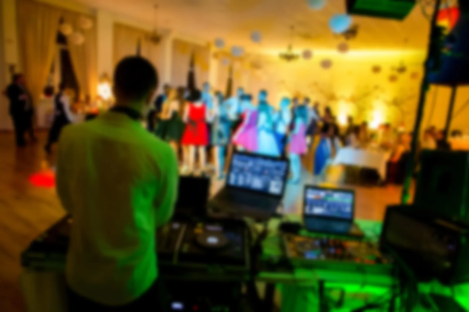 DJ at a wedding reception playing with wedding laser lights, with a crowd behind