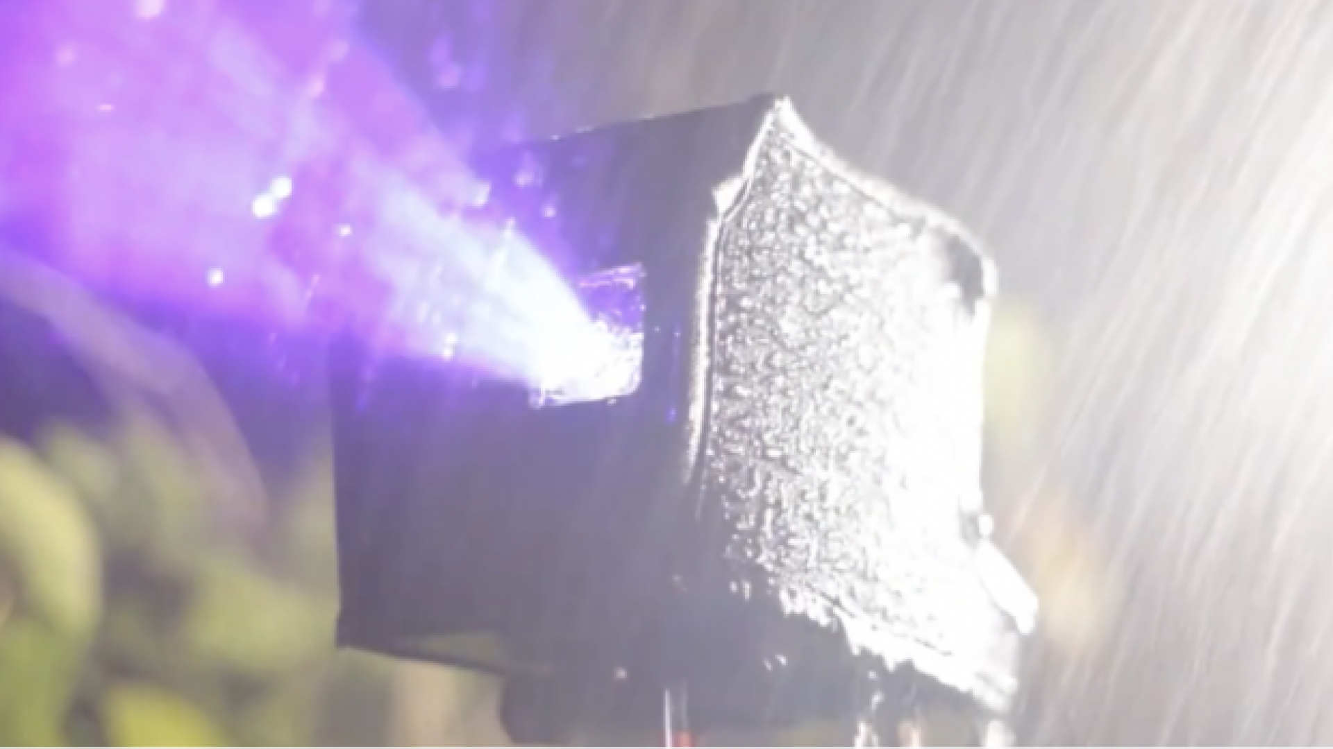 Bot A lasercube laser light projector with rain cover, projecting outdoor laser advertising during heavy run.